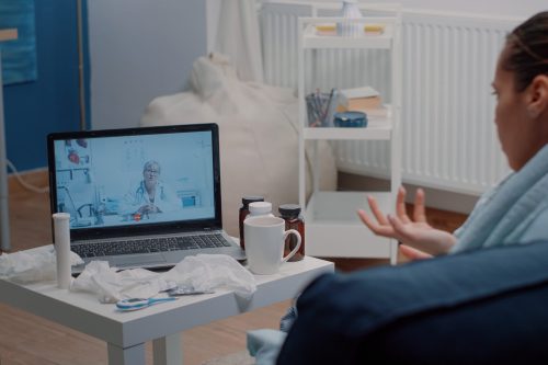 Patient with headache using video call for telemedicine and telehealth, asking doctor about treatment to cure pain and flu symptoms. Woman talking to specialist on online remote conference